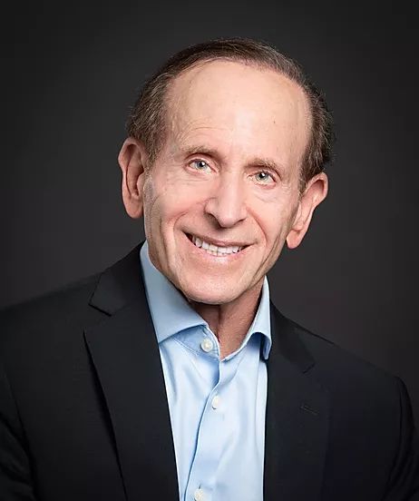 Smiling man in suit against dark background.